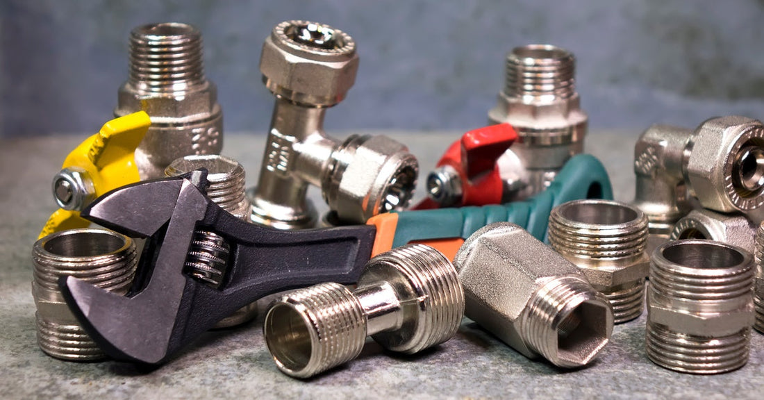 A pile of spare washers and boiler parts with a heavy-duty wrench. The spare parts are shiny stainless steel.