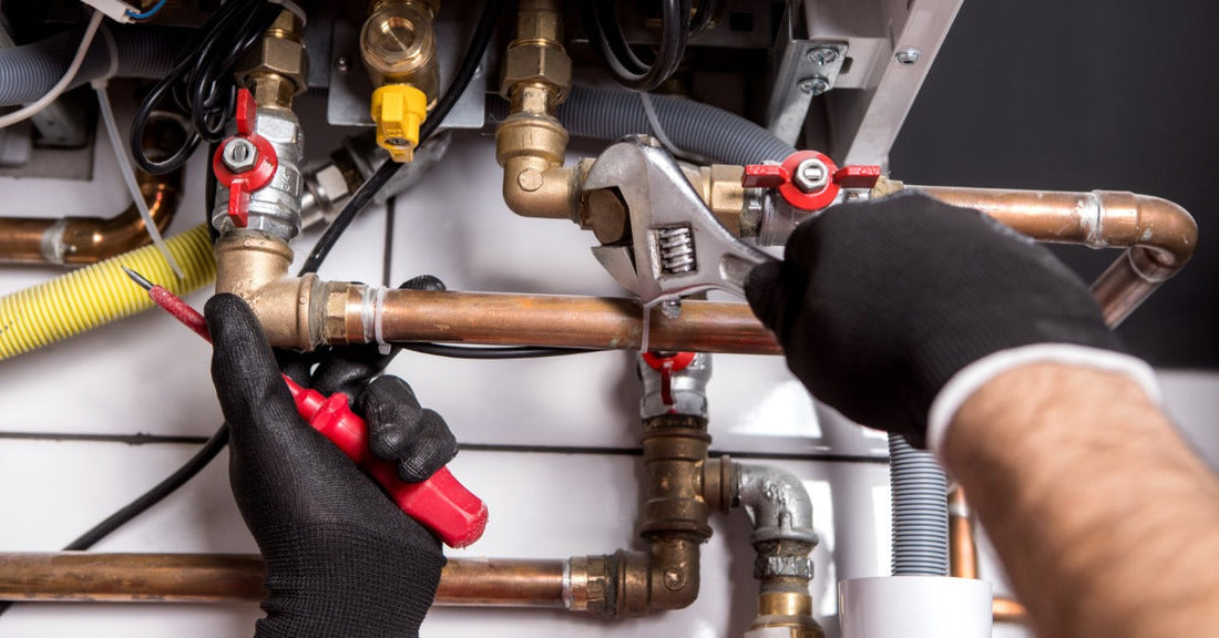 An engineer's hands wear black work gloves as they use tools to adjust the cutoff system on the boiler unit.