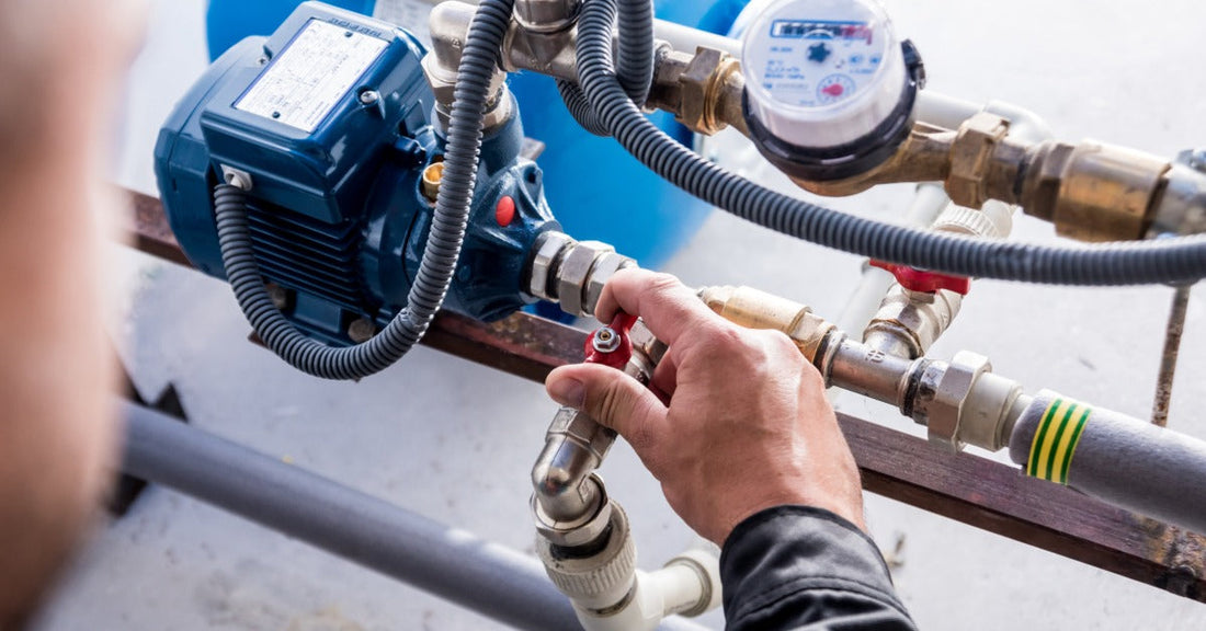 An industrial professional close to the steam check system. Their right hand is on the valve component.