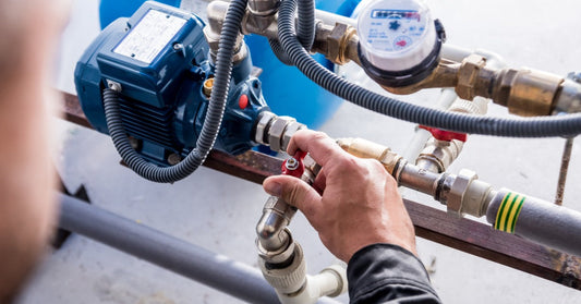 An industrial professional close to the steam check system. Their right hand is on the valve component.
